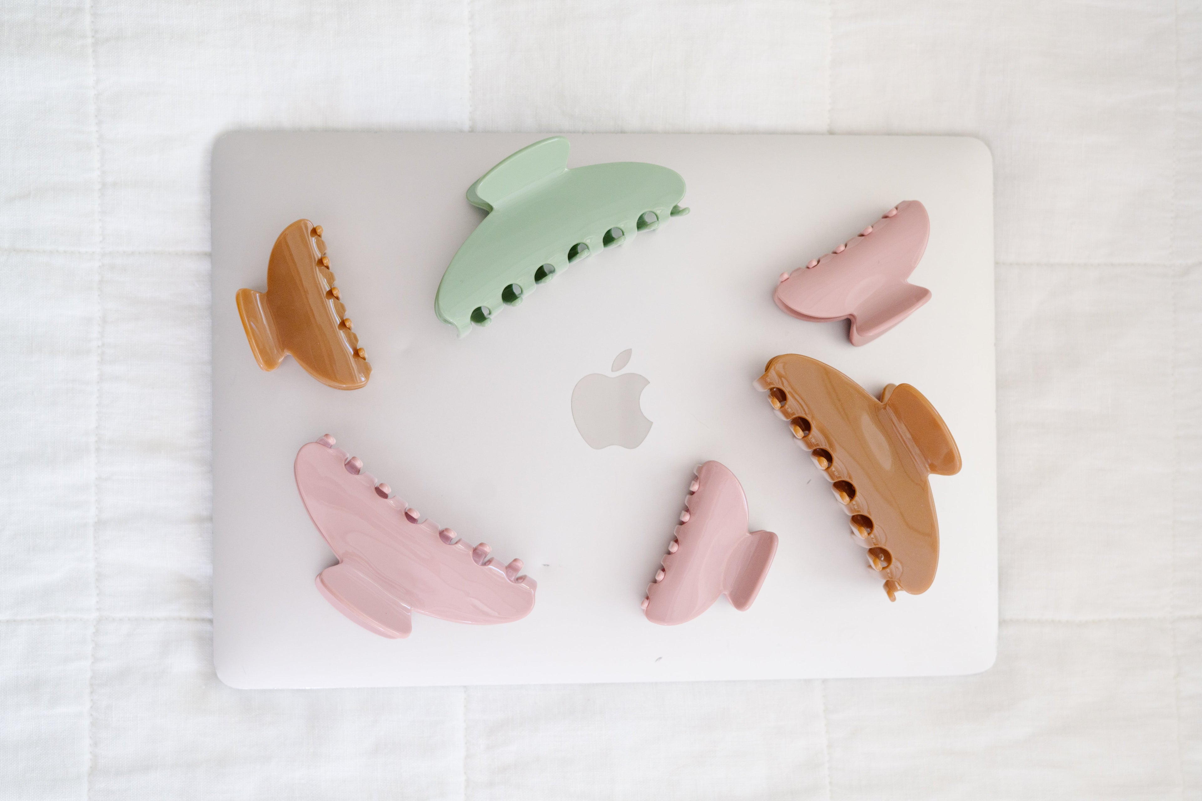 Set of colorful hair clips on a laptop with an Apple logo.